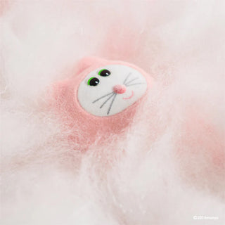 Close-up of a fluffy pink cat with a white face and green eyes on a soft pink background.