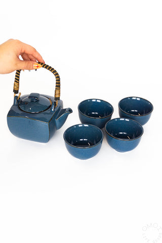 Blue ceramic teapot with four matching cups on a white background