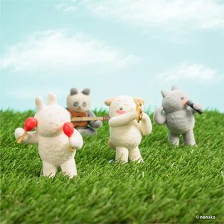 Four plush toys on grass with a blue sky background