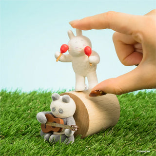 Two small animal figurines on a grassy surface with a hand interacting with one of them.