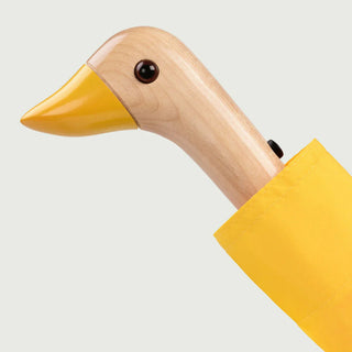 Wooden duck-shaped object with a yellow beak on a light gray background