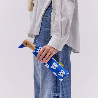 Person holding a blue umbrella with duck head design against a white background