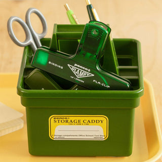 Green storage caddy with office supplies on a wooden surface