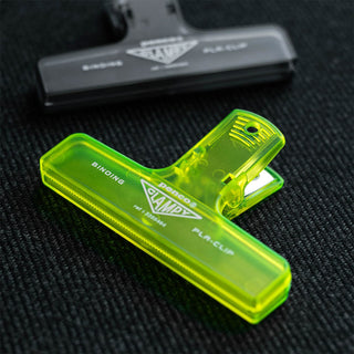 Neon yellow plastic clip on a textured black surface with a blurred background