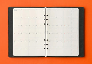 PLOTTER 2027 open black spiral-bound planner with calendar.