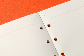 Close-up of perforated grid paper notebook with an orange background
