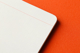 Close up of notebook with grid pages on an orange background
