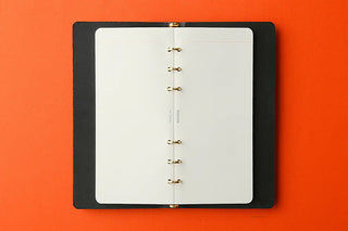 Black ring-bound notebook on an orange background