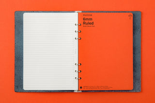 Binder with notebook inserts with orange cover and white lined pages on an orange background