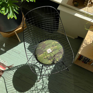 Black wire chair with a camouflage cushion on a wooden floor.
