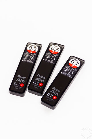 Three black Pentel lead refills on a white background