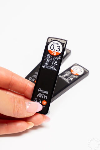 Hand holding a Pentel Ain mechanical pencil with a white background