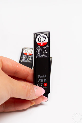 Pentel Ain lead refill with a hand holding it on a white background