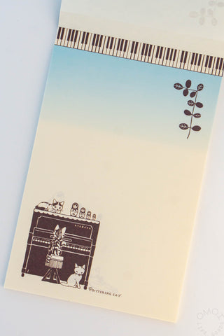 Memo page with piano keys at the top, gradient cover design, and illustrations of cats around the piano with Matryoshka dolls