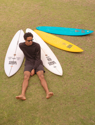Sunglasses lifestyle scene: person and surfboards outdoors; sunglasses not clearly visible