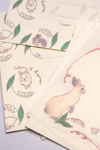 Set of stationery items with a rabbit and lily of the valley illustrations on a light background