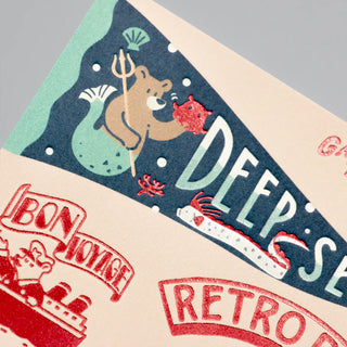 Decorative paper with mermaid bear illustration, text, and ship design on a gray background