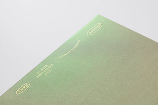 Green notebook with gold embossed text on a light gray background