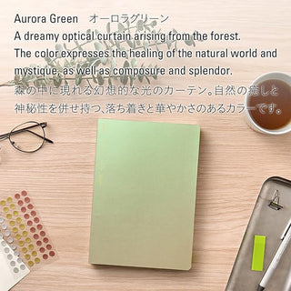 Green notebook on a wooden surface with text about the color 'Aurora Green'.