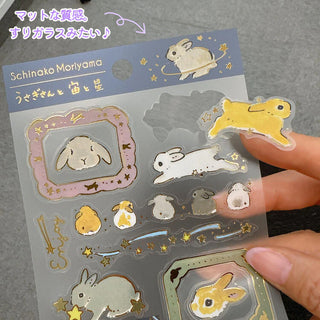 Sheet of rabbit-themed stickers with a hand holding them