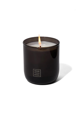 Black candle with a lit wick on a white background