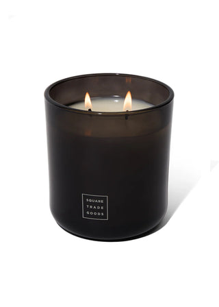 Black candle jar with a lit candle inside on a white background