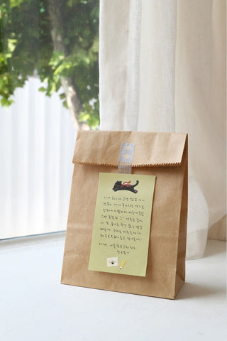 Kraft paper bag with green note and black cat sticker