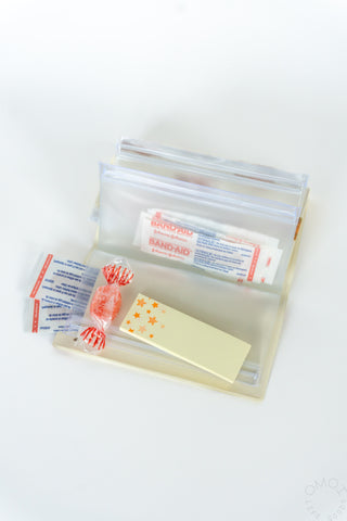 Opened brown bear pattern 5 pocket pouch with candy and band-aids on a white background