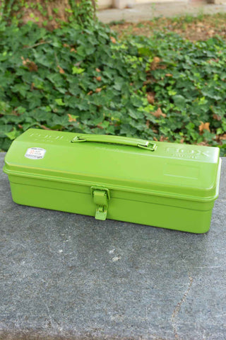 Green toolbox on a stone surface with greenery in the background