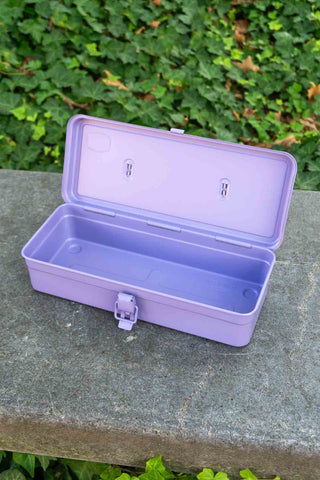 Purple toolbox on a stone surface with green foliage in the background