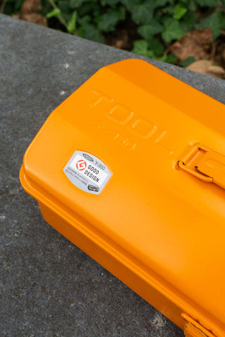 Orange tool box with a visible 'Good Design' label on a concrete surface.