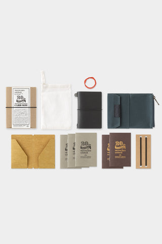 Collection of small leather goods including wallet card cases, and notebooks on a white background.