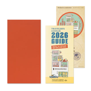 Orange notebook featuring 'Traveler's notebook 2026 Guide' and stickers on a white background.
