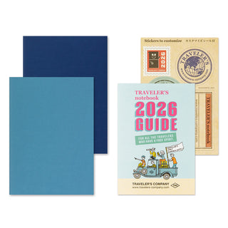 Traveler's notebook with blue cover, 2026 guidebook, and stickers on a white background