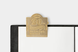 Gold clip on a black notebook with 'Traveler's 20th Anniversary' text
