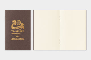 Two notebooks, one brown with gold text and the other opened with beige pages on a light gray background.