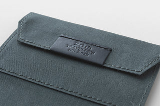 Blue fabric pouch with a brand label on a light gray background