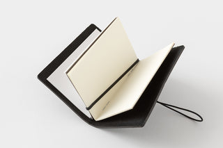 Black leather-bound notebook with open pages on a white background