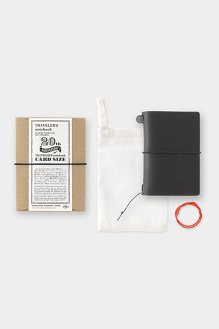 Black notebook, white pouch, and red band on a light gray background