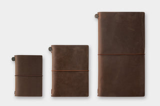 Three brown leather notebooks of different sizes on a white background
