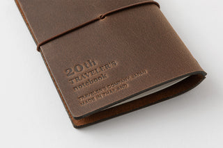 Brown leather notebook with '20th Traveler's notebook' embossed on a white background