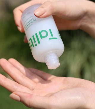Talitha Koum essence soo bottle dispensing onto open palm, white cap and green text