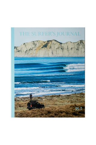 Cover of 'The Surfer's Journal' with a person standing overlooking the ocean.