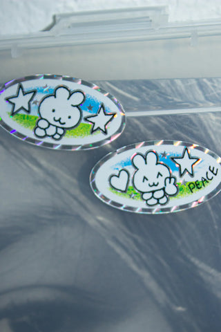 Two cartoon character stickers with stars and text on a reflective surface