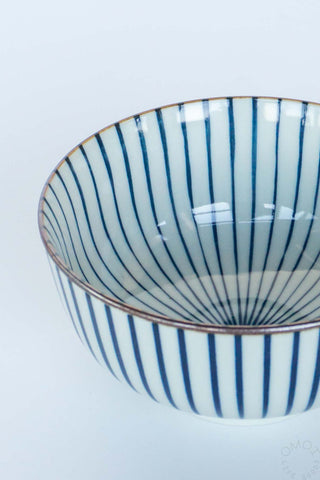 Ceramic bowl with blue vertical stripes on a light gray background