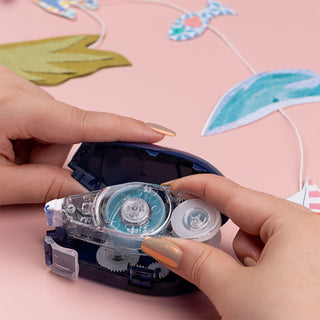 Person using a clear tape dispenser with colorful paper in the background