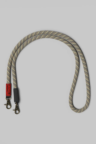 A braided rope bag strap with a gray and beige pattern, with bronze hardware on a solid gray background.