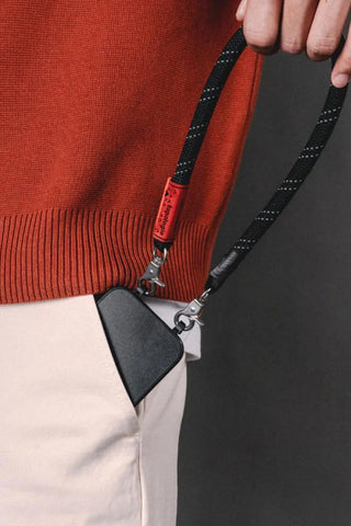 Black and red reflective wrist strap with clips holding a small pouch
