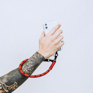Reflective wrist strap with black hardware and orange/red ends for a phone