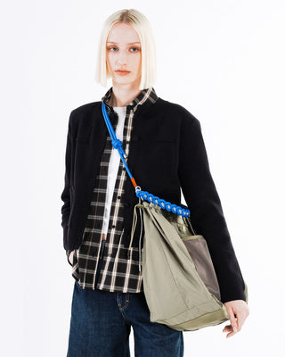 Person wearing a green bag with a braided bright blue adjustable strap across their body